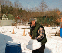 Чтобы запастись мягкой снеговой водой, дачники набивают снегом свободные бочки.
